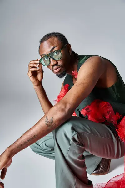 Attractive african american man stylish outfit squatting on gray backdrop, fashion concept — Stock Photo