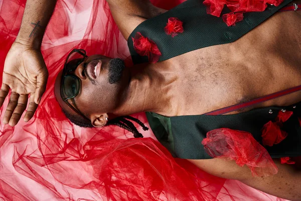 Attrayant homme afro-américain à la mode avec des lunettes de soleil en tenue tendance couché sur le sol, la mode — Photo de stock