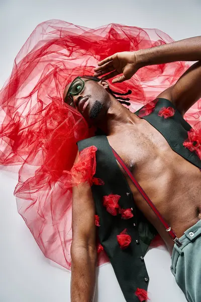 Alluring fashionable african american man with sunglasses in vibrant attire lying on floor, fashion — Stock Photo