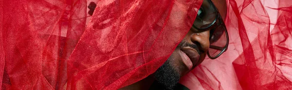 Retrato de jovem afro-americano com tecido de tule vermelho deitado no chão, conceito de moda, banner — Fotografia de Stock