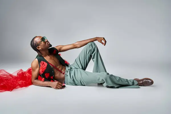 Gut aussehender afrikanisch-amerikanischer Mann in trendiger Kleidung mit rotem Tüll am Boden liegend — Stockfoto