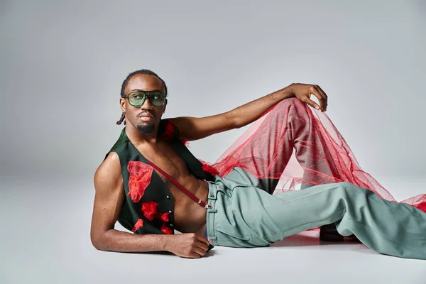 Bell'uomo afro-americano in abbigliamento alla moda con tessuto di tulle rosso disteso sul pavimento — Foto stock