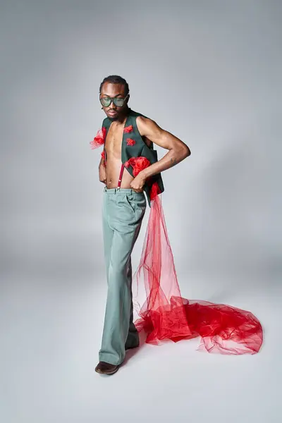 Stylish african american male model with red tulle fabric posing in motion and looking away — Stock Photo