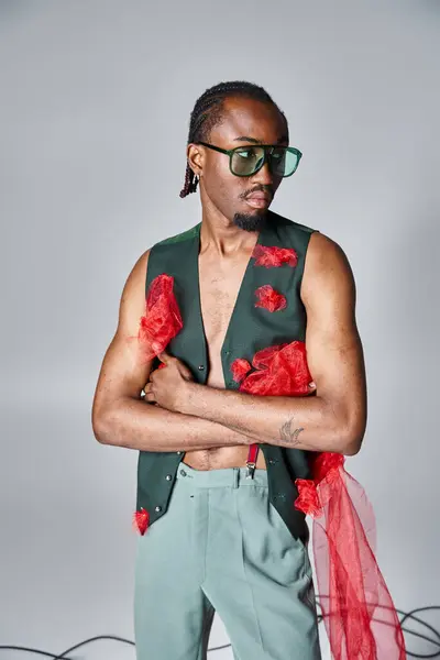 Sofisticado modelo masculino afro-americano com tecido de tule vermelho posando em movimento e olhando para longe — Fotografia de Stock