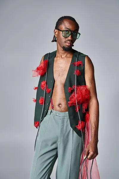 Заманчивый африканский американец в стильных солнцезащитных очках, позирующий в движении и смотрящий в камеру — стоковое фото