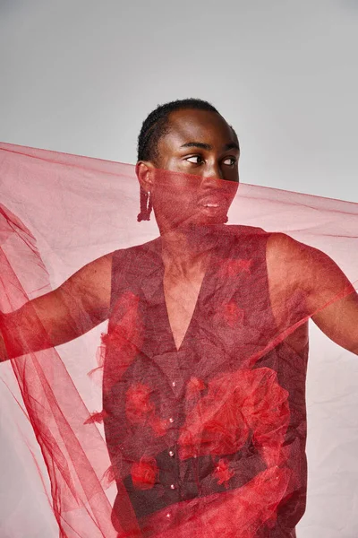Хороший вигляд молода афроамериканська чоловіча модель позує з яскравою червоною тканиною тканини тканини на сірому фоні — стокове фото