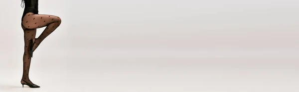 Abgeschnittenes Banner einer schicken Frau in Korsett, gepunkteten Strumpfhosen und High Heels posiert auf weißem Hintergrund — Stockfoto