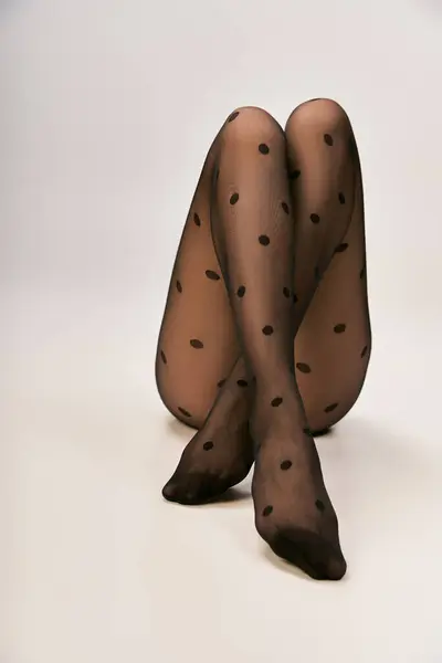 Corte tiro de jovem mulher em preto polka ponto meia-calça posando no fundo branco, pernas cruzadas — Fotografia de Stock