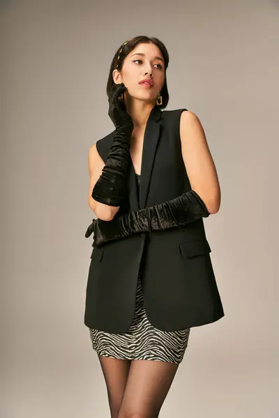 Belle femme asiatique en tenue élégante avec gants et bandeau posant sur fond gris, charmant — Photo de stock