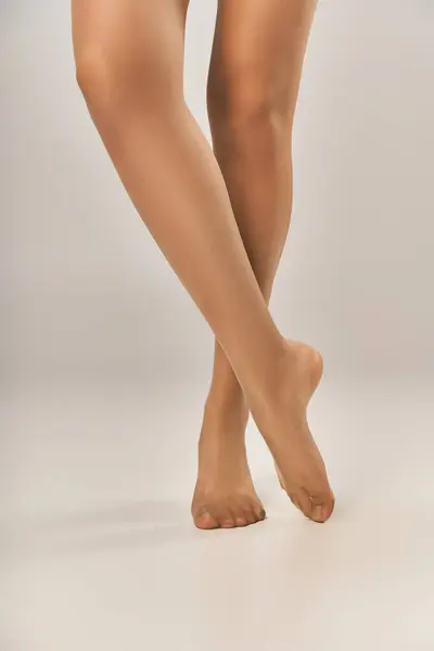 Partial view of young woman in beige seamless pantyhose posing on grey background, hosiery — Stock Photo