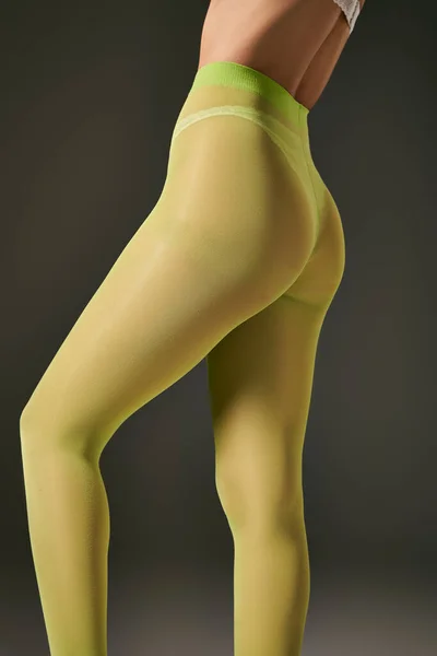 Обрезанное фото молодой женщины в зеленых колготках, позирующей на сером фоне, концепция чулочно-носочных изделий — стоковое фото