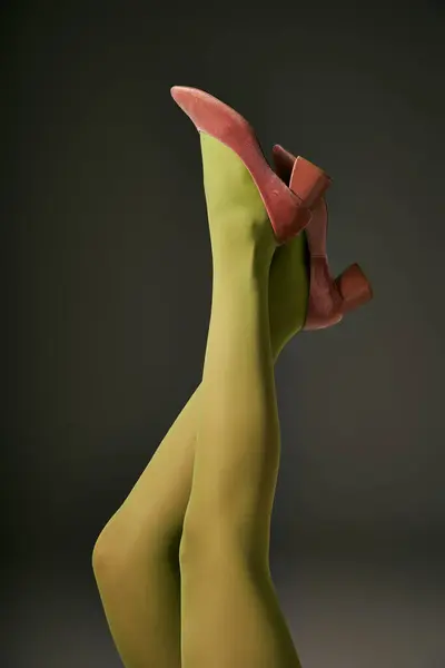 Vista ritagliata di giovane donna in collant di nylon verde sdraiato su sfondo grigio scuro, concetto di calzetteria — Foto stock