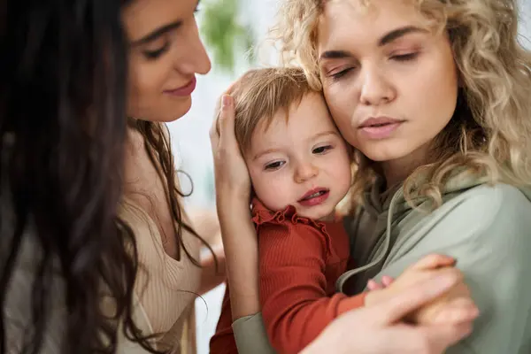 Attrayant couple lesbien attentionné tenant leur bébé fille dans les mains et la réconfortant, concept de famille — Photo de stock