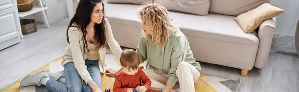 Feliz casal lésbico brincando com brinquedos com sua filha criança em casa, parentalidade moderna, banner — Fotografia de Stock