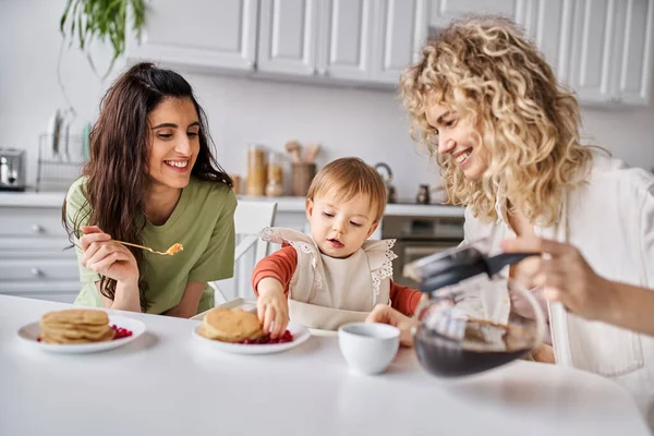 Joyous attractive lgbt couple having delicious breakfast with their baby girl, family concept — Stock Photo