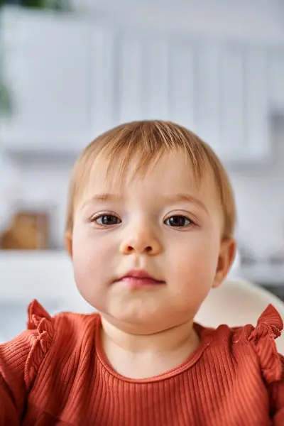 Gros plan de petite fille charmante en pull orange essayant d'atteindre la caméra avec ses mains — Photo de stock