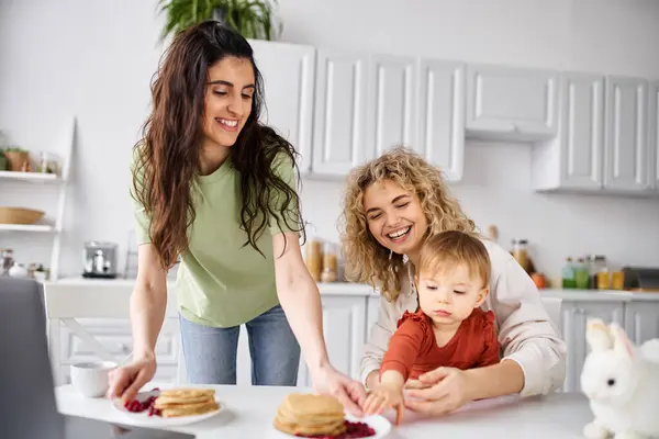 Attraktive fröhliche lesbische Paare mit Pfannkuchen beim Frühstück mit ihrem kleinen Mädchen, Familienkonzept — Stockfoto