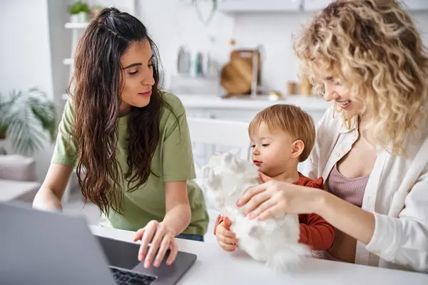 Bella coppia lesbica in homewear guardando film con la loro bambina sul computer portatile, concetto di famiglia — Foto stock