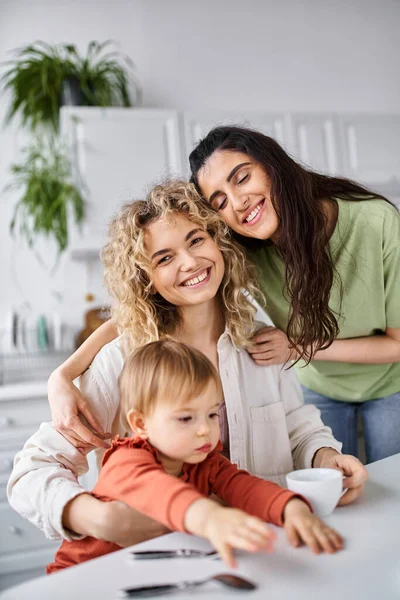 Jolly attractive lgbt couple in homewear having great time with their daughter at breakfast, family — Stock Photo