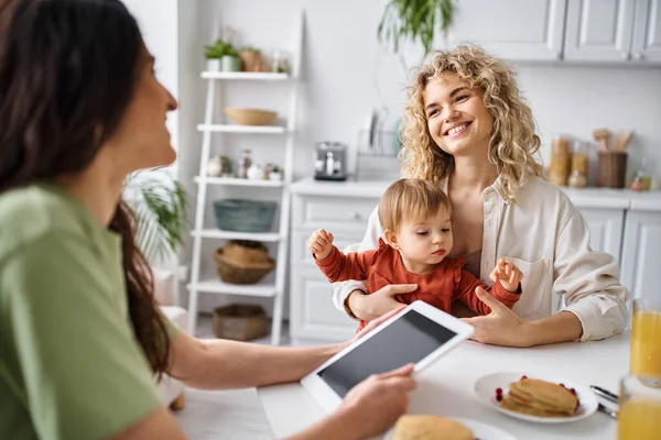 Пов'язана пара lgbt сніданок зі своєю дитиною і дивиться на планшет, сімейна концепція — стокове фото