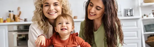 Jolly lesbian couple in homewear spending time together with their pretty toddler daughter, banner — Stock Photo