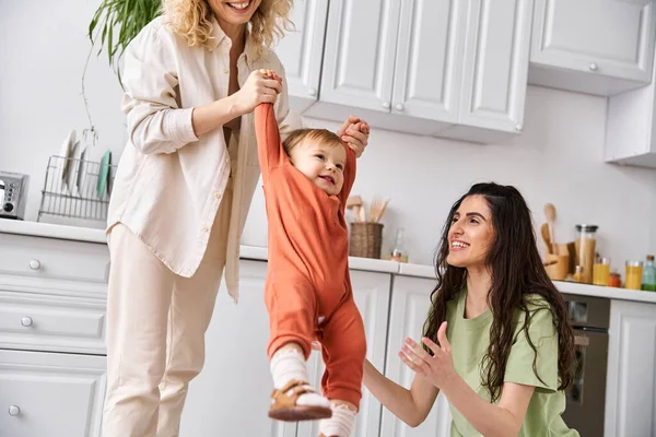 Beautiful cheerful lesbian couple playing actively with their toddler daughter, modern parenting — Stock Photo