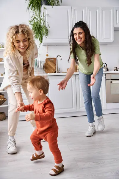Atractivo alegre lgbt pareja jugando con su bonita hija en la cocina, concepto de familia - foto de stock