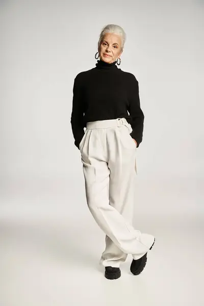 Piena lunghezza della donna d'affari di mezza età in elegante abbigliamento posa con le mani in tasche sul grigio — Foto stock