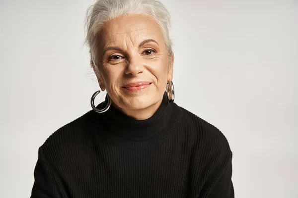 Business portrait, happy middle aged business woman in turtleneck looking away on grey backdrop — Stock Photo