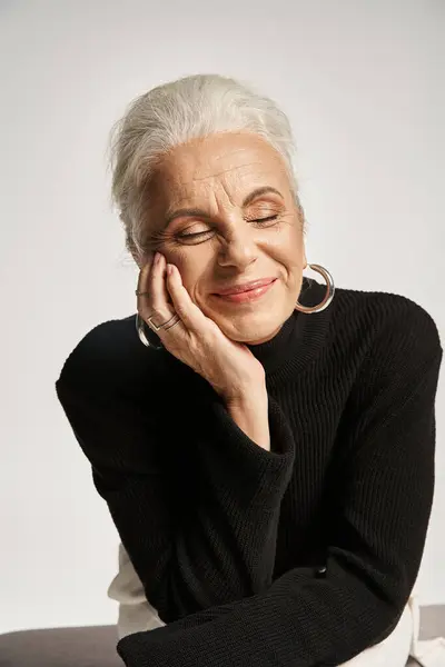 Business portrait, pleased middle aged business woman with closed eyes posing in turtleneck on grey — Stock Photo