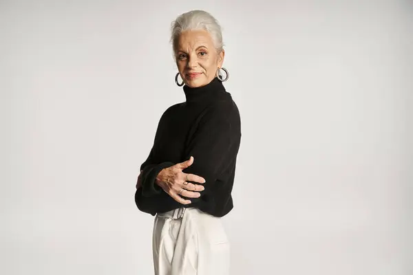 Mujer de negocios de mediana edad feliz en elegante traje casual elegante posando sobre fondo gris - foto de stock