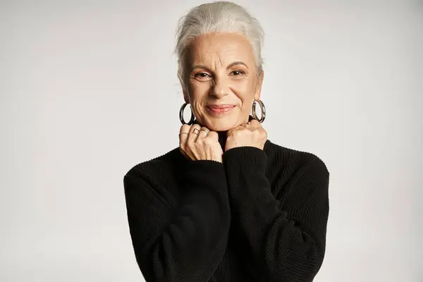 Mujer de negocios de mediana edad feliz en elegante traje casual elegante posando sobre fondo gris - foto de stock