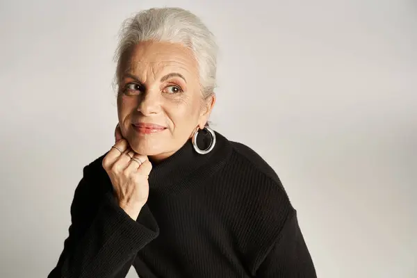 Portrait of happy middle aged business woman in elegant attire and hoop earrings on grey background — Stock Photo