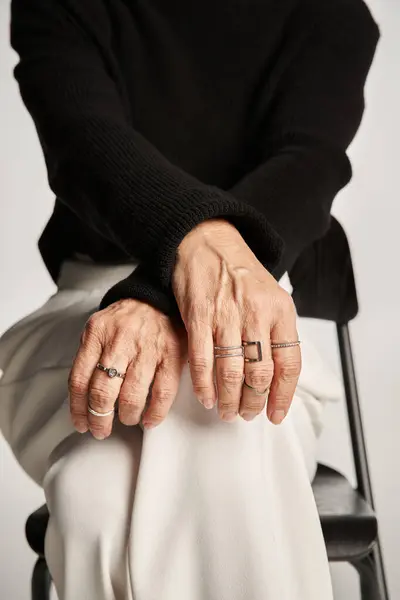 Mujer de negocios de mediana edad recortado en traje casual inteligente y anillos en los dedos sentados en la silla - foto de stock
