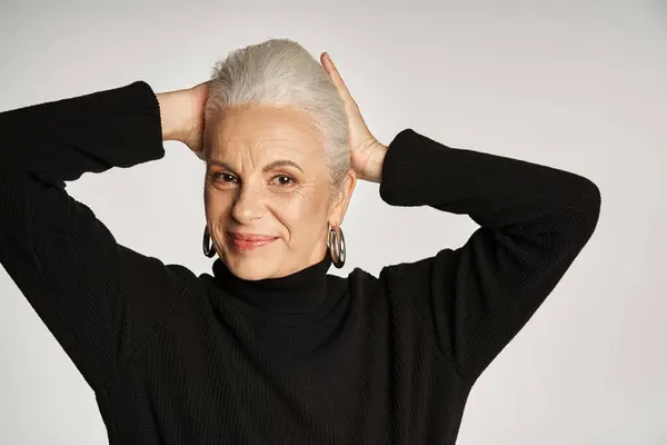 Portrait of happy middle aged business woman in elegant attire and hoop earrings on grey background — Stock Photo