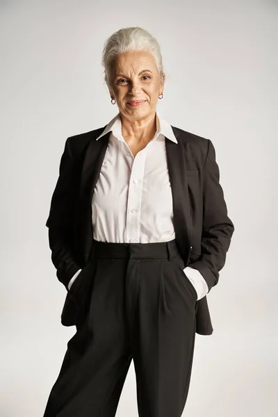 Ritratto di felice donna d'affari di mezza età in camicia bianca e pantaloni in piedi con le mani in tasca — Foto stock