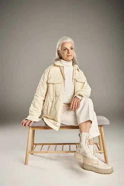 Beautiful and grey haired middle aged woman in elegant attire posing on grey background — Stock Photo