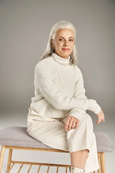 Beautiful and grey haired middle aged woman in elegant attire posing on grey background — Stock Photo