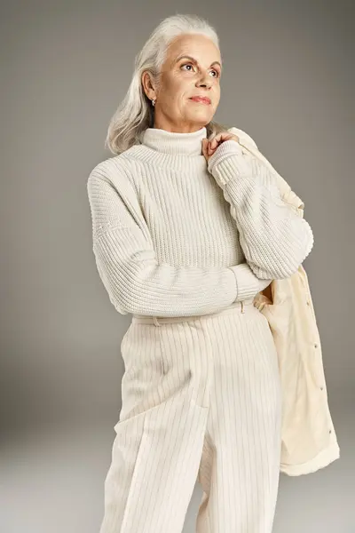 Beautiful and grey haired middle aged woman in elegant attire posing on grey background — Stock Photo
