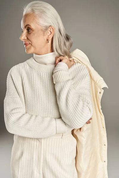 Beautiful and grey haired middle aged woman in elegant attire posing on grey background — Stock Photo