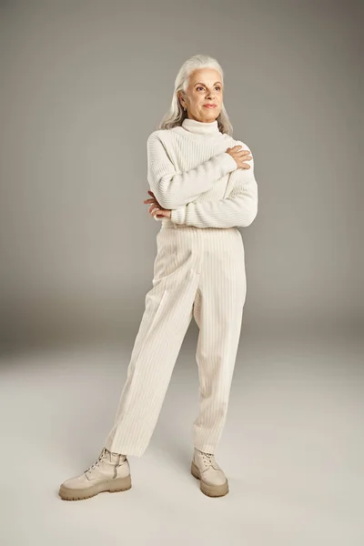 Beautiful and grey haired middle aged woman in elegant attire posing on grey background — Stock Photo