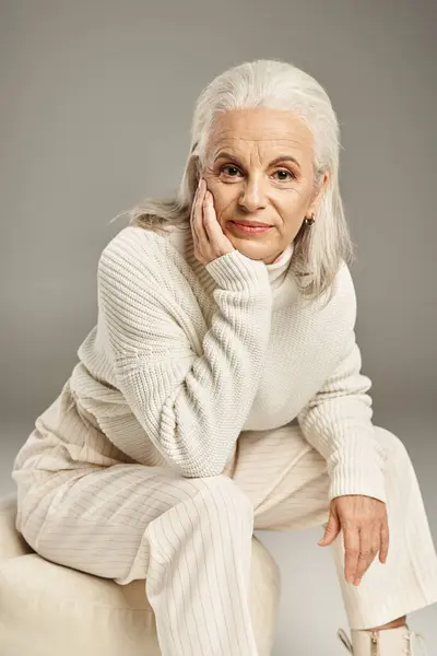 Beautiful and grey haired middle aged woman in elegant attire posing on grey background — Stock Photo