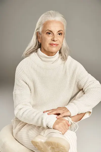Beautiful and grey haired middle aged woman in elegant attire posing on grey background — Stock Photo