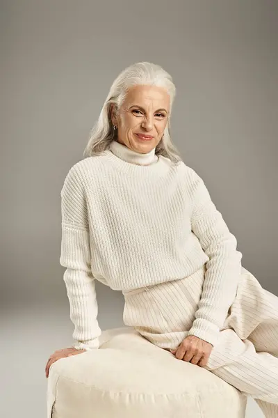 Bella e dai capelli grigi donna di mezza età in elegante abbigliamento in posa su sfondo grigio — Foto stock