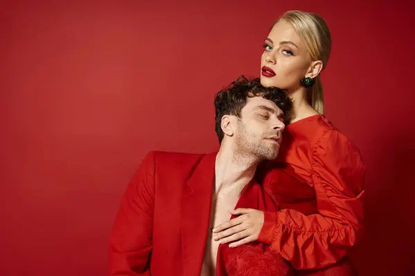 Giovane donna seducente con labbra rosse e capelli biondi abbracciando bell'uomo in abbigliamento rosso, stile — Foto stock