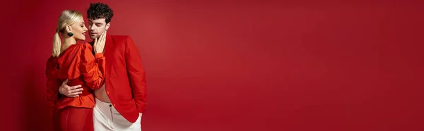 Банер жінки з червоними губами, що торкається обличчя красивого чоловіка в стильному вбранні на яскравому тлі — стокове фото