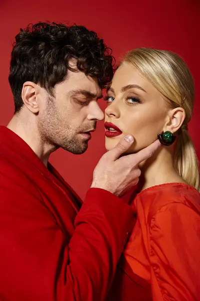 Bel homme touchant visage de belle femme blonde avec des lèvres rouges sur fond vibrant, mode — Photo de stock
