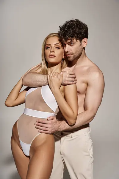 Homme torse nu avec corps musclé embrassant femme séduisante sur fond gris, couple sexy — Photo de stock