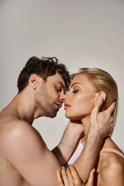 Side view of handsome man kissing attractive blonde woman on grey background, sexy couple — Stock Photo