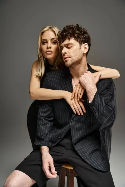 Homem bonito em traje de designer vermelho posando com modelo loira em fundo vibrante, casal na moda — Fotografia de Stock